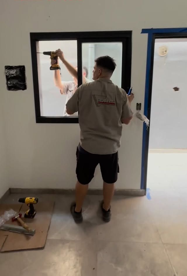 Colocador instalando una ventana de aluminio negro